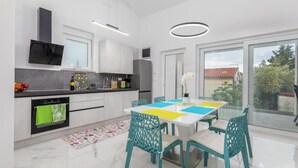 A modern kitchen with a dining area, featuring a large window, a built-in oven, and a refrigerator. - Gorgeous home in Betiga (Betiga)