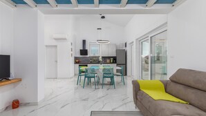 A modern living room with a sofa and a TV, a dining area with chairs and a table, and a kitchen with cabinets and appliances. - Gorgeous home in Betiga (Betiga)