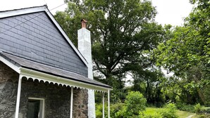 A stone house with a covered porch and a chimney. - Peaceful spacious cottage close to mountain walks and beaches (Machynlleth)