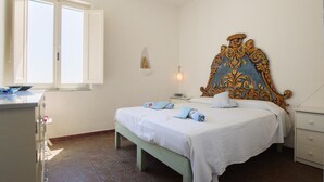 Ein Schlafzimmer mit einem Bett, einem Nachttisch, einer Kommode und einem Fenster.