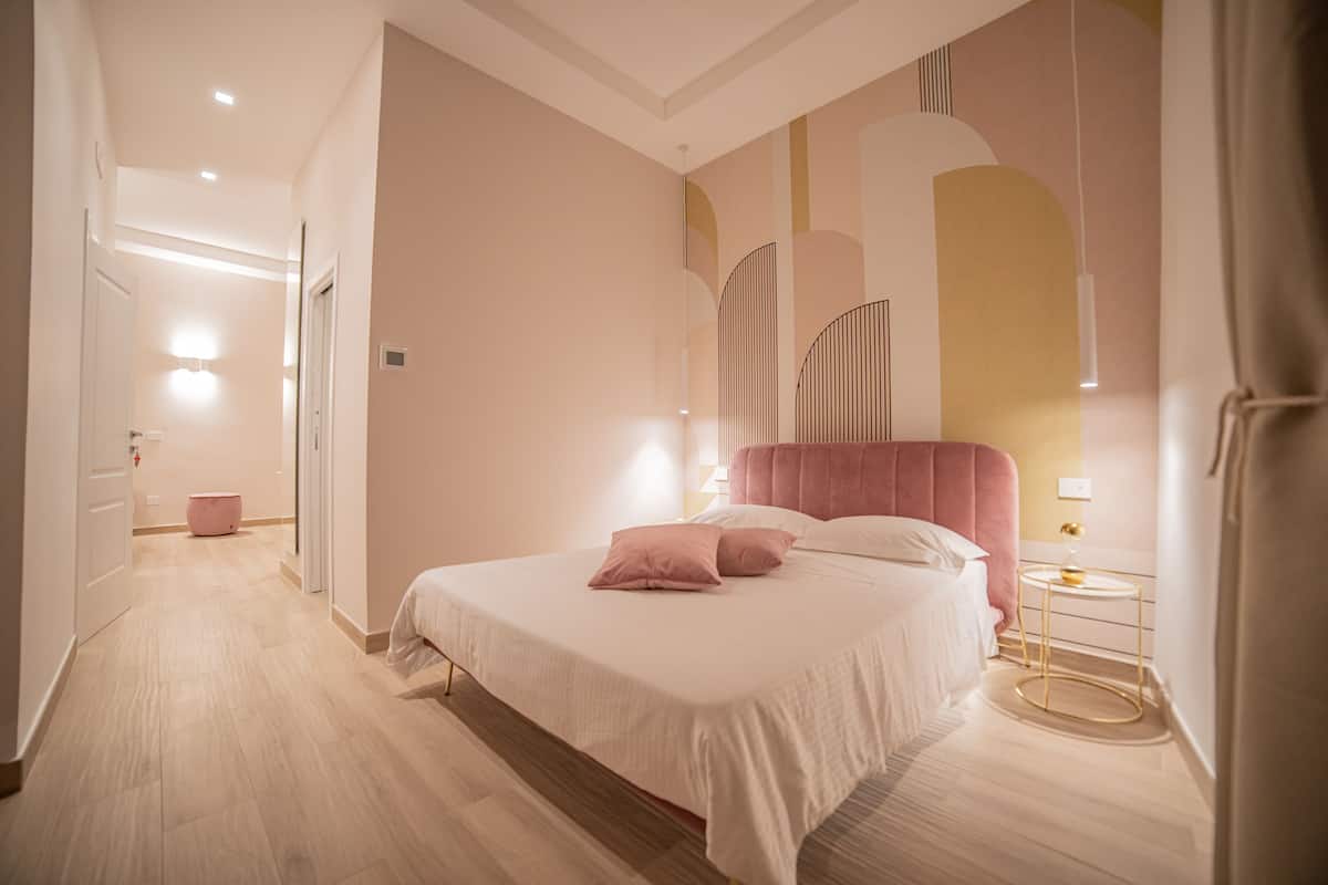 A modern hotel room with a large bed, a bedside table, and a nightstand.