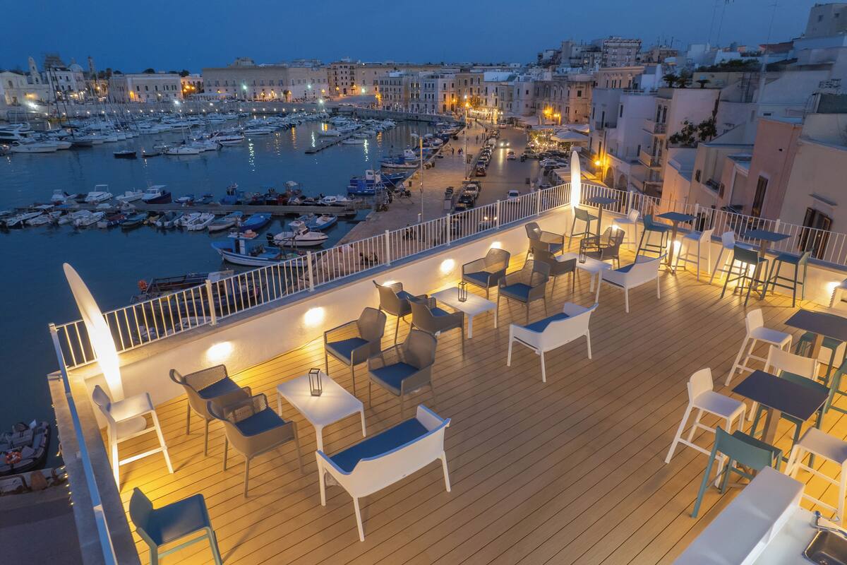 A deck with outdoor seating and a view of a marina with boats.