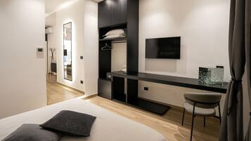 A modern bedroom with a bed, a desk, a chair, a TV, and a wardrobe.