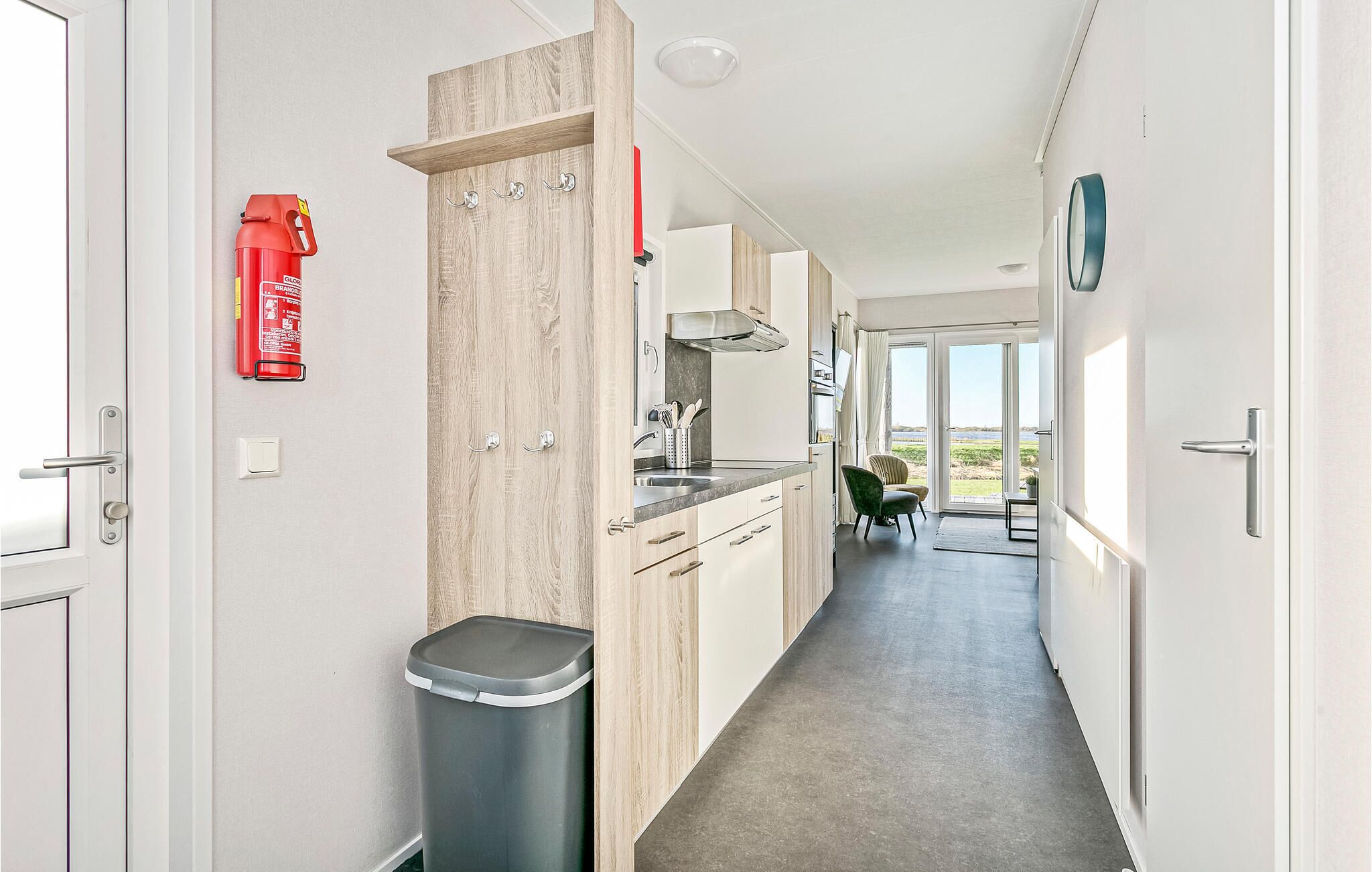 Un pasillo estrecho con una zona de cocina, un extintor y un cubo de basura.