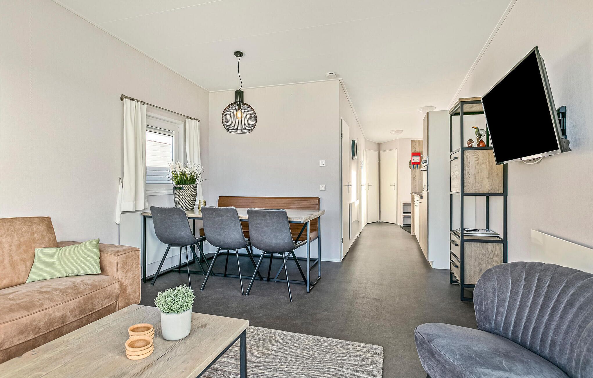 Una sala de estar moderna con un sofá, una mesa de centro con una planta y un comedor con sillas y una mesa.