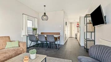 Una sala de estar moderna con un sofá, una mesa de centro con una planta y un comedor con sillas y una mesa.