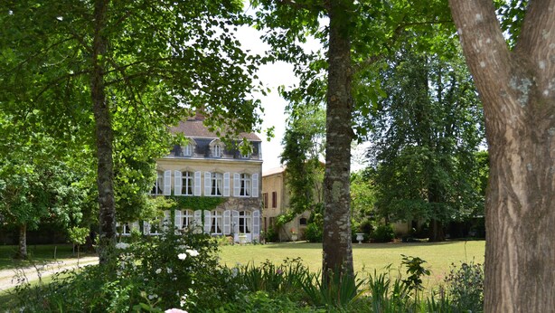 A large, historic building with a symmetrical facade, surrounded by lush greenery and mature trees. - The Orangerie in the grounds of Chateau St Justin (Saint-Justin)