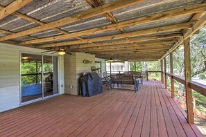Une terrasse couverte avec un plancher en bois, un banc et un barbecue.