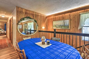 Un coin repas avec une nappe bleue, des murs en bois, un miroir rond et un tableau.