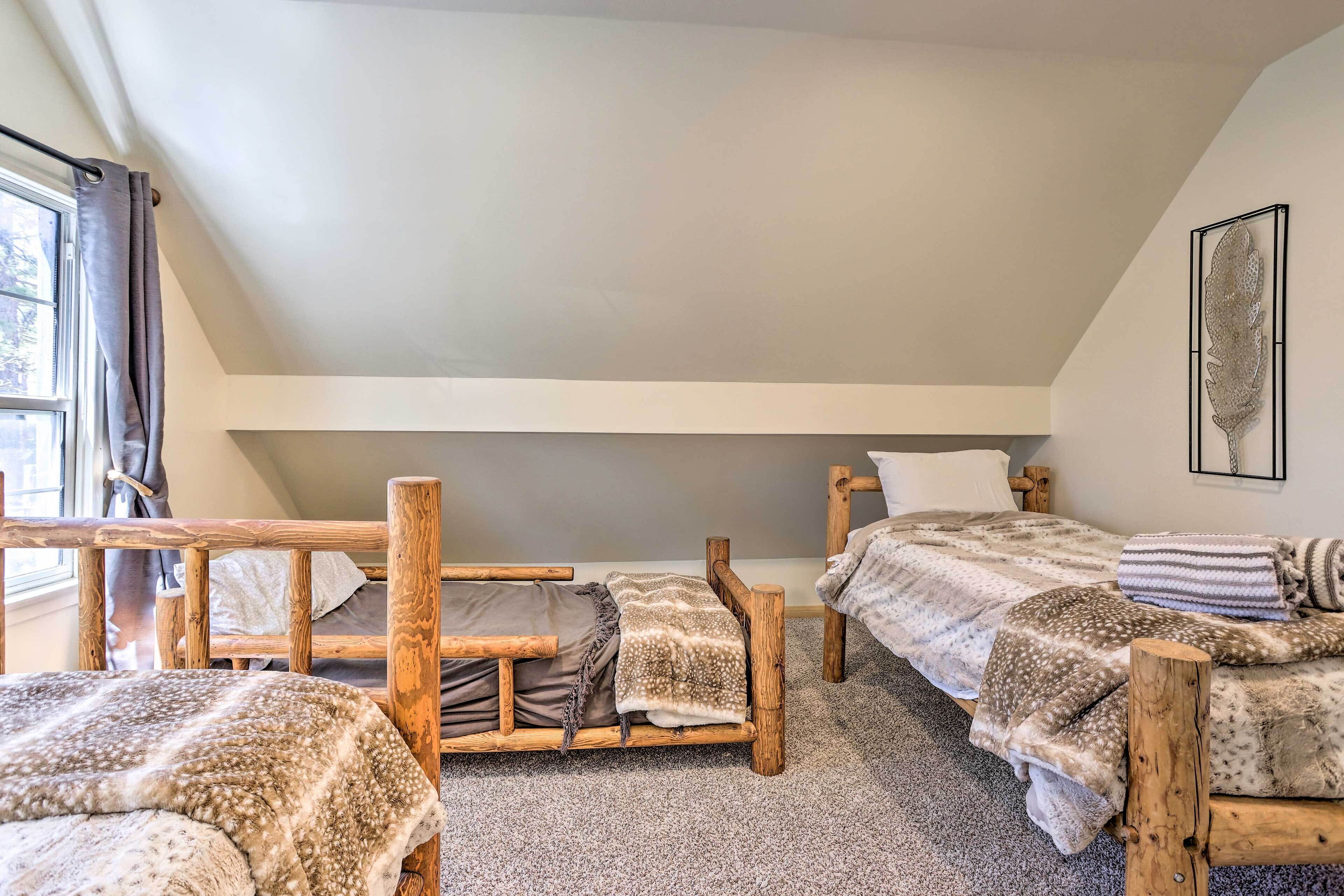 Um quarto aconchegante com duas camas de madeira, uma janela com cortinas e uma obra de arte pendurada na parede.