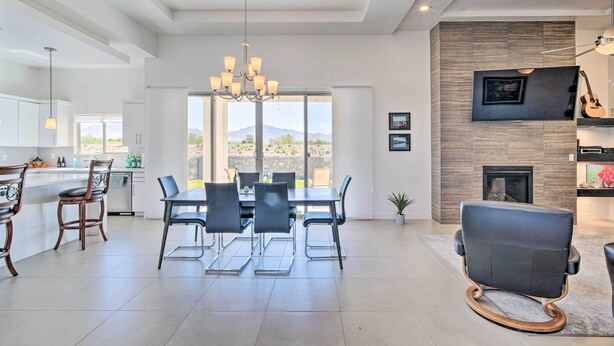 A spacious living area with a dining table, chairs, a chandelier, a fireplace, and a television mounted on the wall. - Upper Valley El Paso Home w/ Hiking Access On-Site (El Paso)