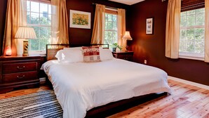 A bedroom with a large bed, two bedside tables, a nightstand, and a window with curtains. - Lovely Home near the river and 5 mins to downtown AVL. (Asheville)