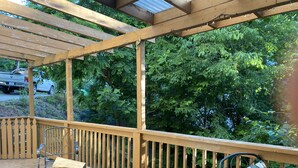 A wooden deck with a fire pit and metal chairs, surrounded by a wooden railing and trees. - Lovely Home near the river and 5 mins to downtown AVL. (Asheville)
