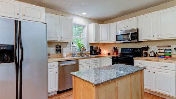 A modern kitchen with white cabinets, a stainless steel refrigerator, a microwave, and a dishwasher. - Lovely Home near the river and 5 mins to downtown AVL. (Asheville)