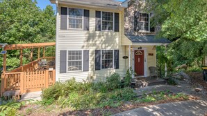 A two-story house with a porch, a stone facade, and a well-maintained garden. - Lovely Home near the river and 5 mins to downtown AVL. (Asheville)
