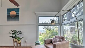 Ein modernes Wohnzimmer mit großem Fenster, einem braunen Ledersofa und zwei Topfpflanzen.