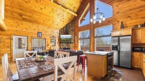 A spacious log cabin interior with a kitchen, dining area, and large windows. - LOG CABIN★SECLUDED AUGUST SPECIALS★HOT TUB★GAME ROOM★CONVENIENT★FIRE PIT (Sevierville)