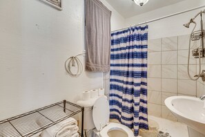 A bathroom with a toilet, sink, shower, and towel rack.