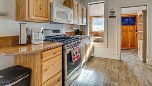 Une cuisine avec des meubles de rangement en bois, un four à micro-ondes, une cuisinière et une machine à café.