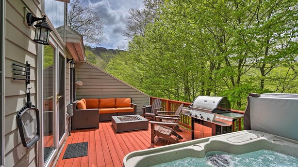 Eine Terrasse mit Gartenmöbeln, einem Whirlpool und einem Grill.