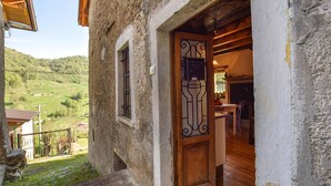 Ein rustikales Steinhaus mit einer Holztür, die zu einem Innenraum mit Essbereich führt.