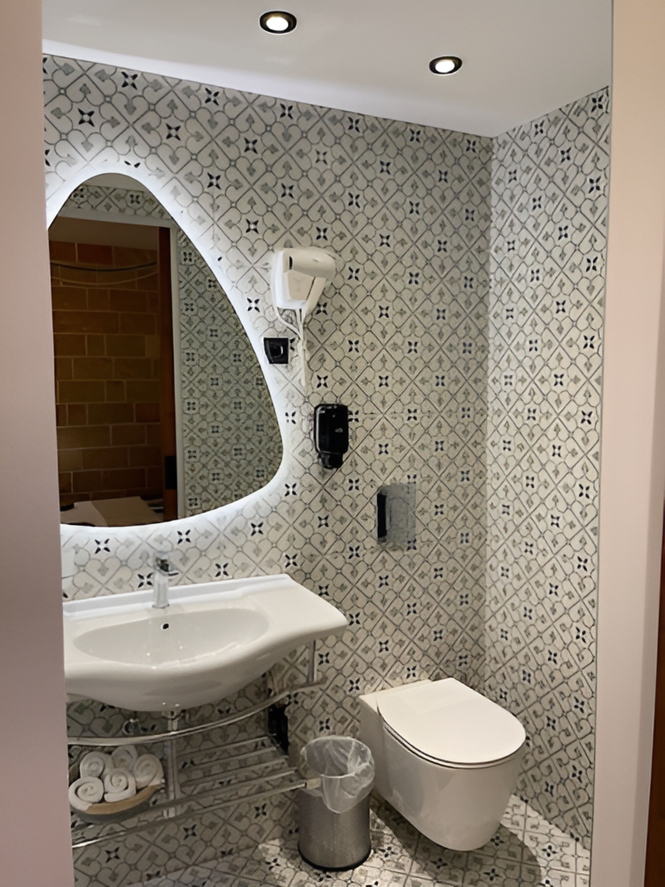 A bathroom with a white sink, a toilet, and a mirror with a decorative frame.