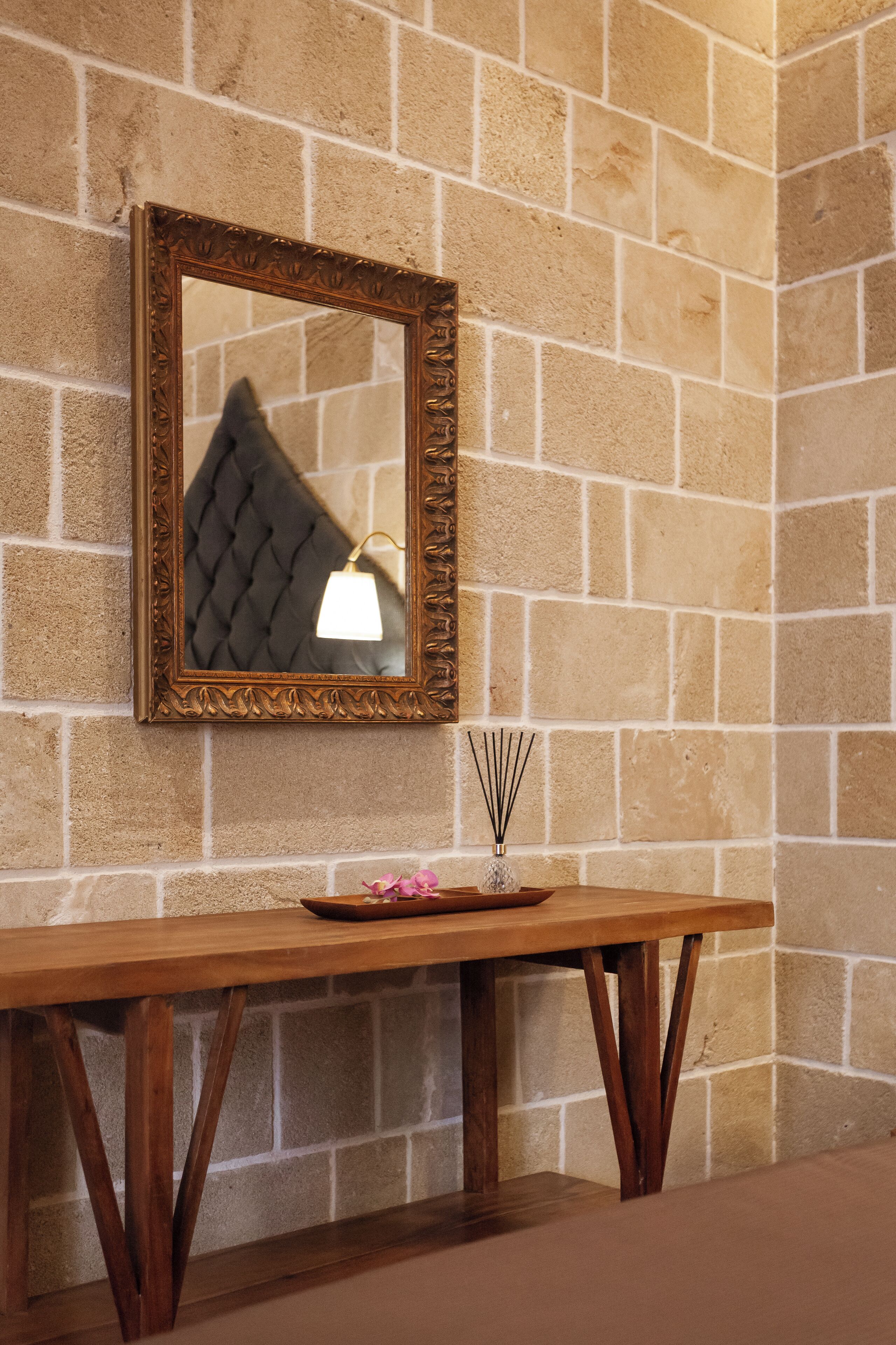 A wooden console table with a decorative mirror and a small vase with a candle.