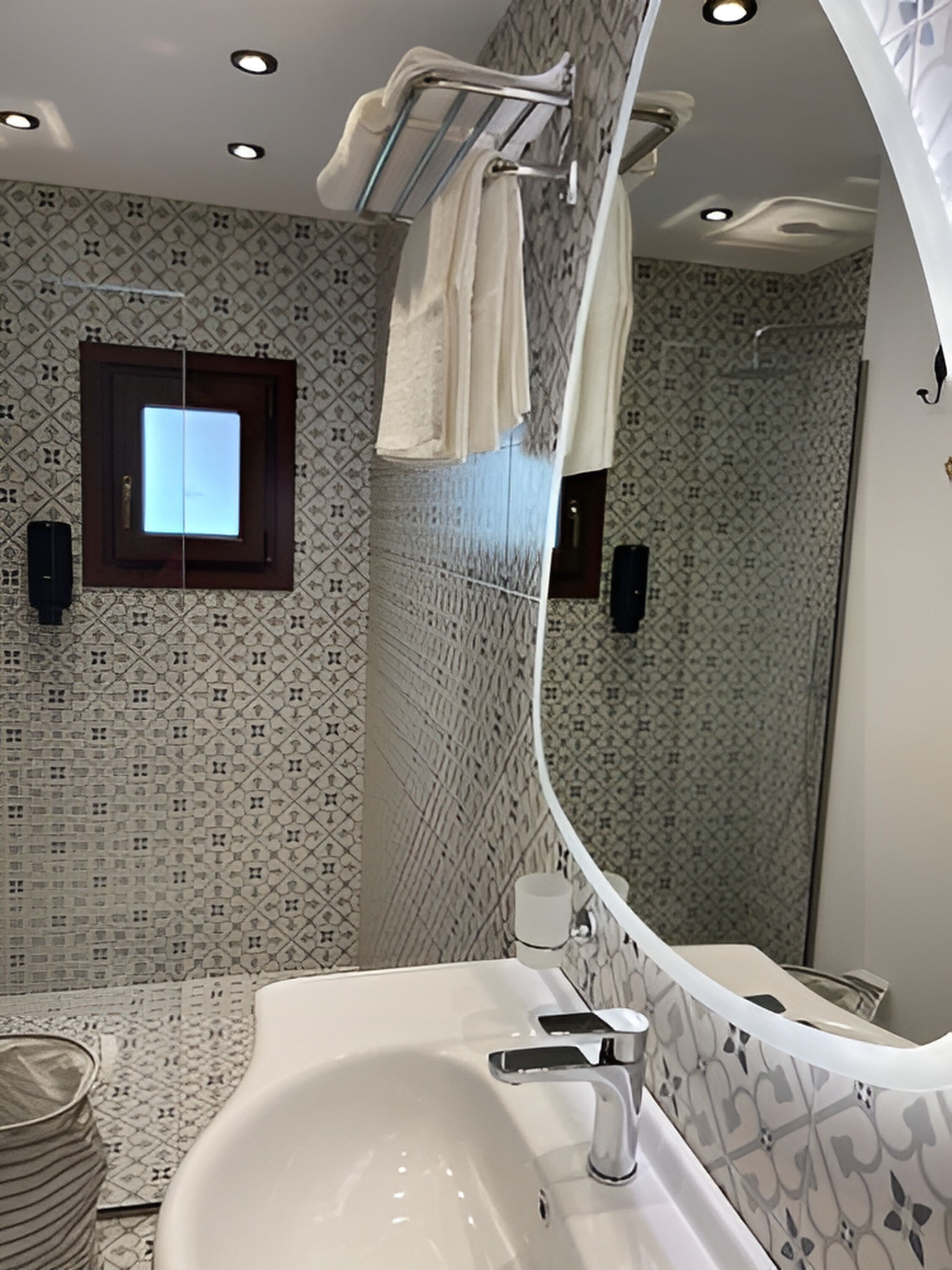 A modern bathroom with a large mirror, a white sink, and a shower area.