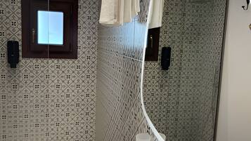 A modern bathroom with a large mirror, a white sink, and a shower area.