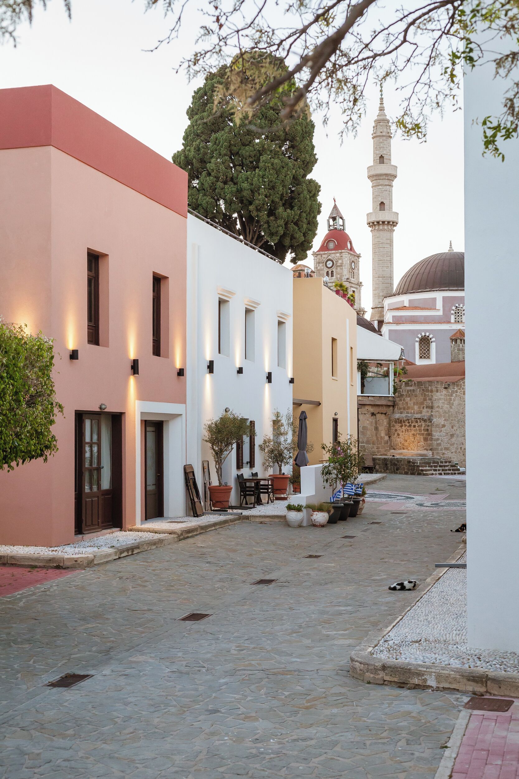 Una estrecha calle empedrada con edificios de arquitectura moderna y una mezquita al fondo.