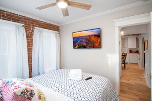 Relax in this inviting bedroom with a large bed, ceiling fan, and wall-mounted TV.