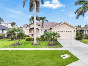 A residential house with a front yard, palm trees, and a garage.
