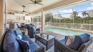 Un espacio al aire libre cubierto con piscina, mobiliario de mimbre y vistas a palmeras.
