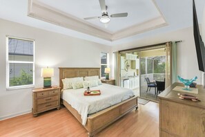 A bedroom with a bed, nightstands, a dresser, a ceiling fan, and a sliding glass door leading to a balcony. - Pet-Friendly Home | Pool, Spa & Steps to Beach (Marco Island)