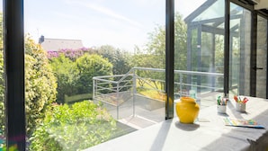 Een balkon met een metalen veiligheidshek, een gele vaas en twee kleine potjes met pennen en potloden.
