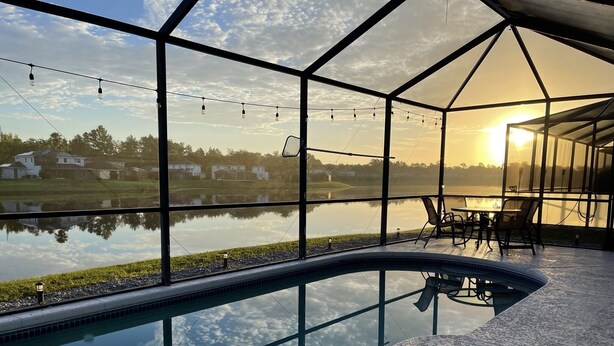 Zona de piscina con vista a un lago y casas al fondo.
