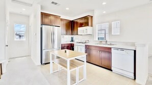 Una cucina moderna con elettrodomestici in acciaio inossidabile, mobili in legno e un piano di lavoro bianco.
