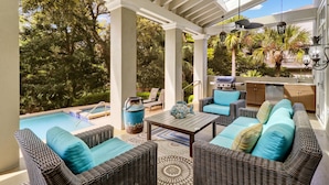 An outdoor patio with wicker furniture, a pool, and a grill area. - Gorgeous 2nd row home directly on the beach path in Palmetto Dunes with pool (Hilton Head Island)