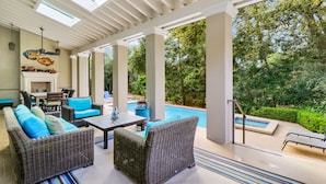A covered outdoor area with wicker furniture, a pool, and a view of the surrounding greenery. - Gorgeous 2nd row home directly on the beach path in Palmetto Dunes with pool (Hilton Head Island)