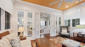 A spacious living room with a large open door leading to a dining area, a comfortable sofa set, a wooden coffee table, and a patterned ottoman. - Gorgeous 2nd row home directly on the beach path in Palmetto Dunes with pool (Hilton Head Island)