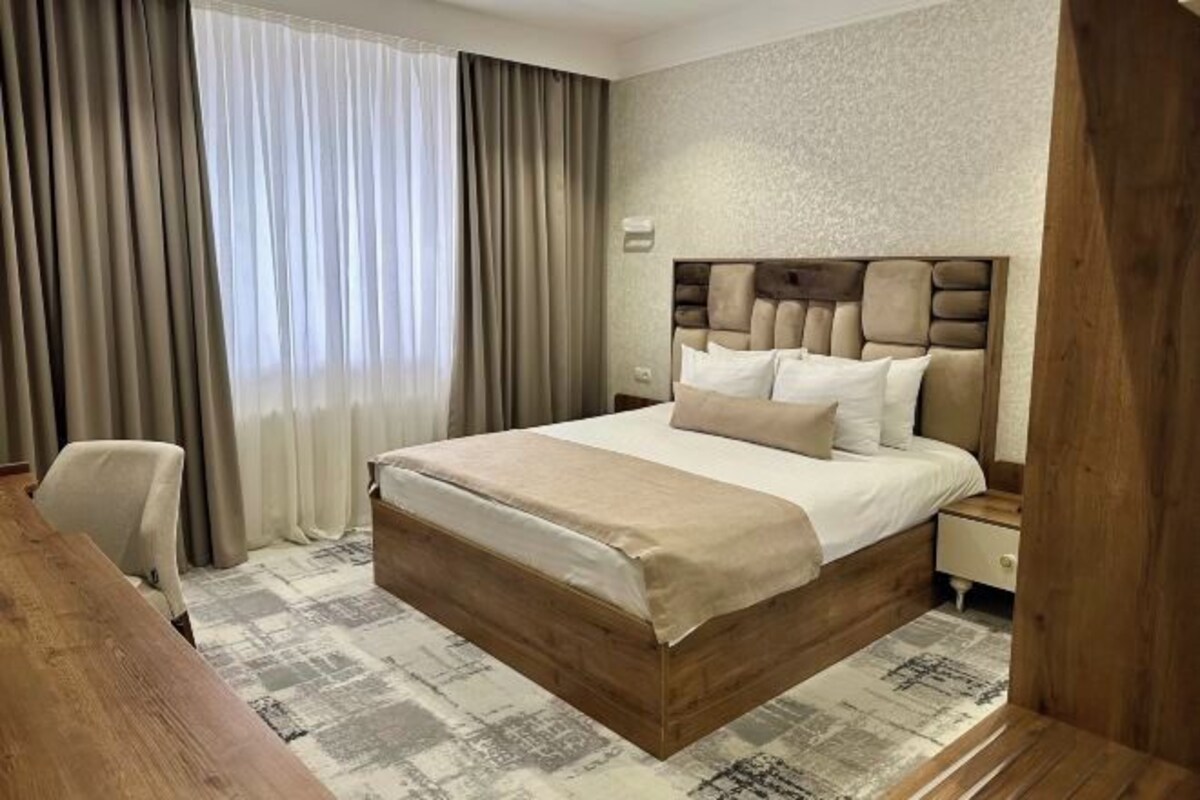Quarto de hotel com uma cama grande, uma escrivaninha de madeira e uma cadeira.