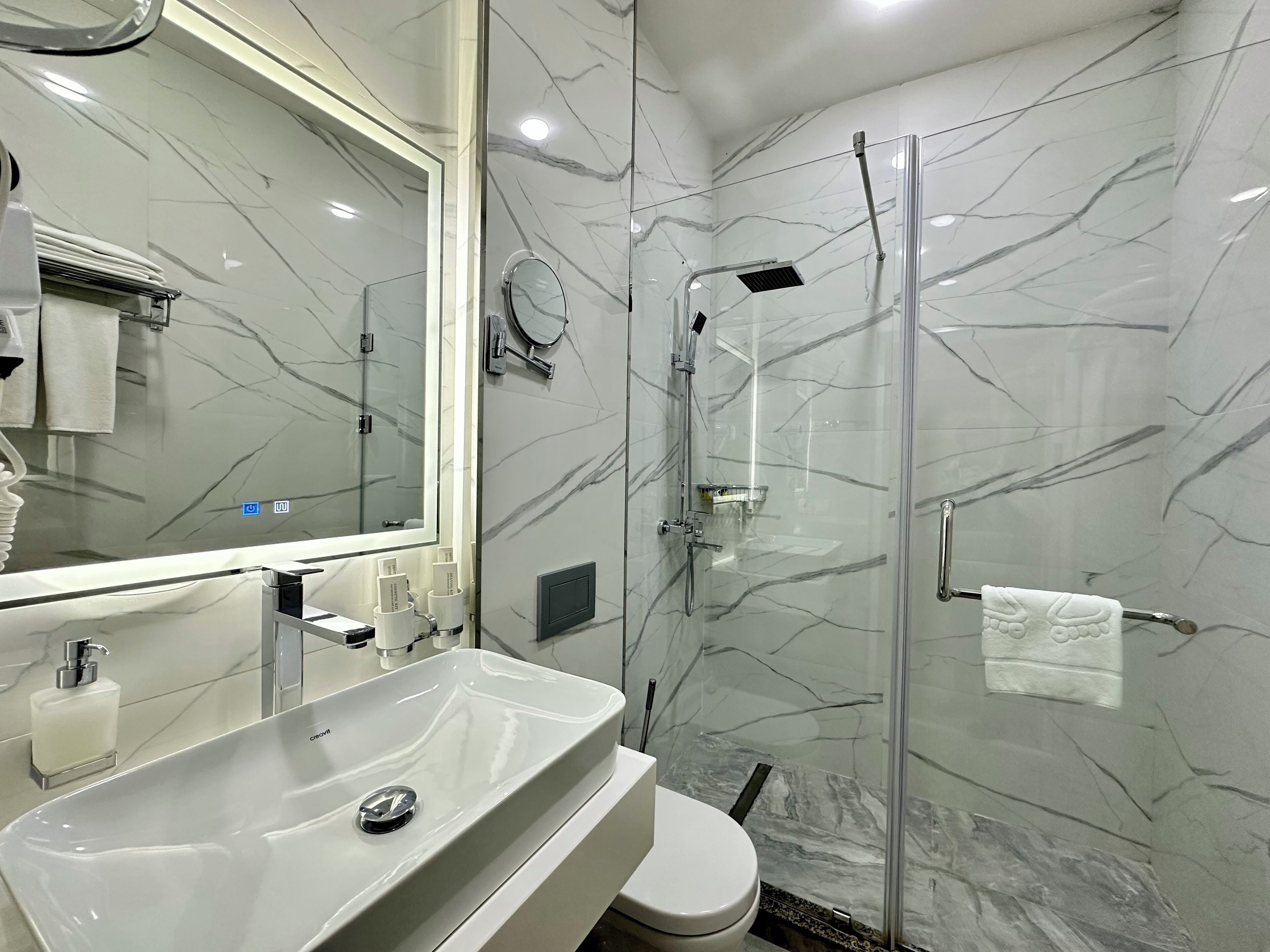 Une salle de bain moderne avec une douche à parois de verre, un lavabo blanc et des toilettes.