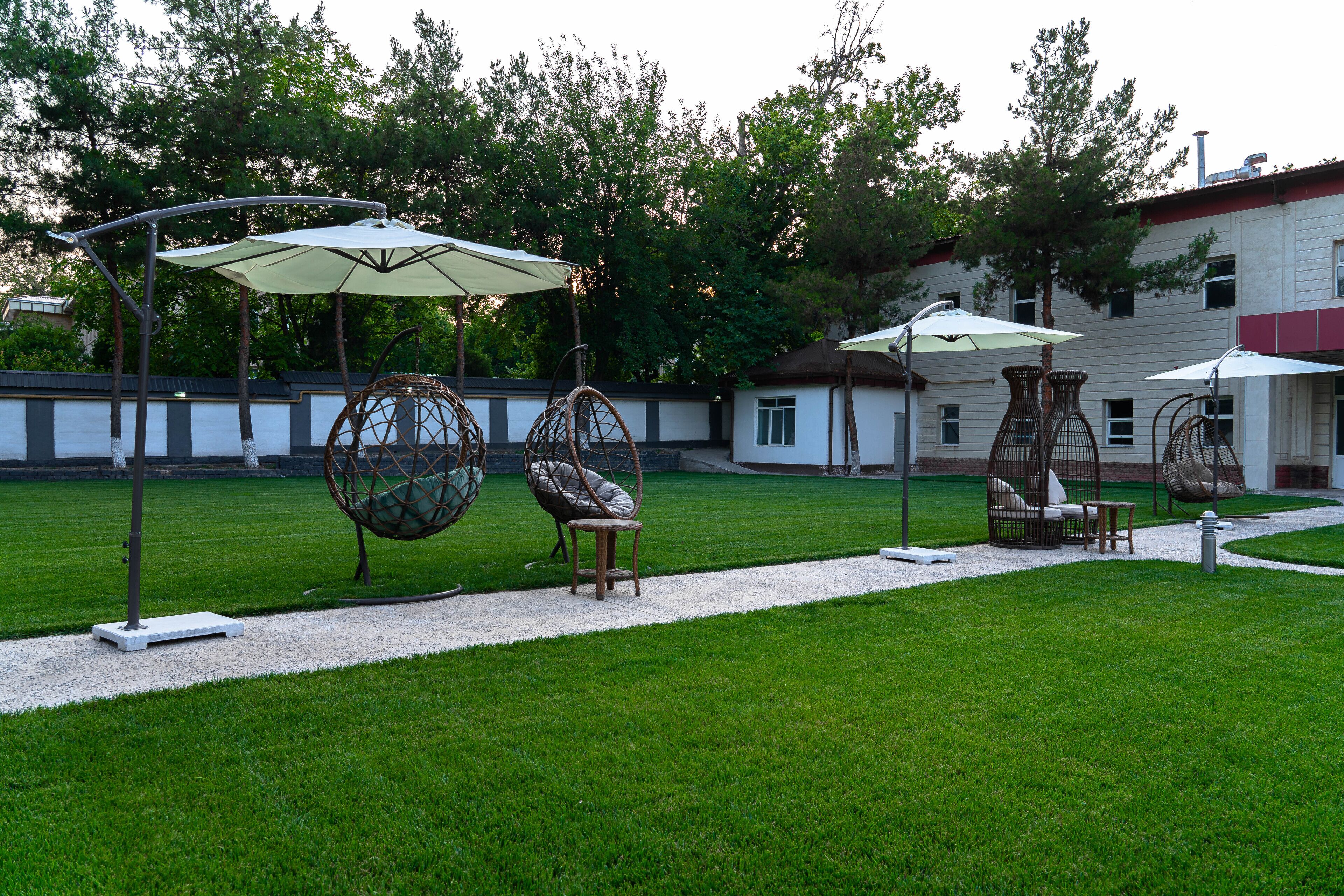 A well-maintained outdoor area with a grassy lawn, seating arrangements, and a building in the background.