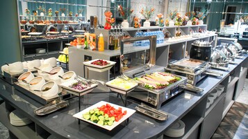 Buffet-pöytä, jossa on tarjolla monenlaista ruokaa ja ruokailuvälineitä.