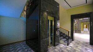 Un interno moderno con una scala in marmo, un pavimento decorato e un corridoio luminoso.