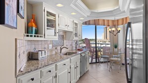 A modern kitchen with white cabinets, a granite countertop, a stainless steel refrigerator, and a view of the city through large windows. - Ocean View, recently updated, 24 hour security + Free Attraction Tickets! (Myrtle Beach)