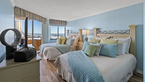 A hotel room with two beds, a vanity with a mirror, and a view of the cityscape. - Ocean View, recently updated, 24 hour security + Free Attraction Tickets! (Myrtle Beach)