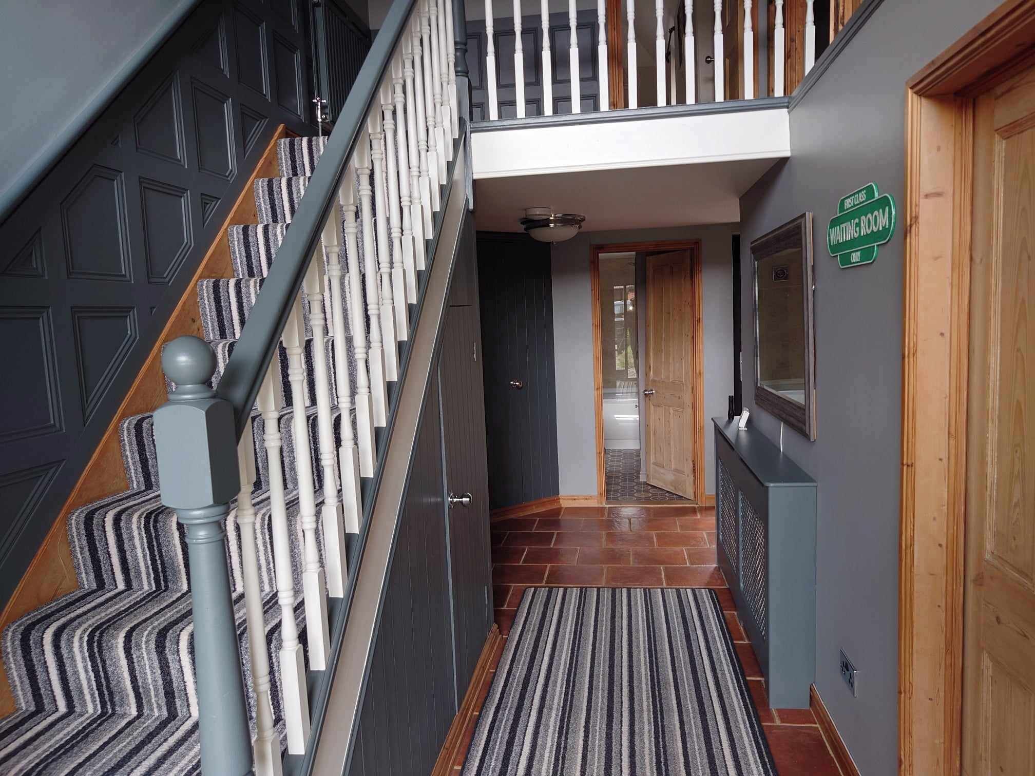 A staircase with a striped carpet leading to a wooden door labeled "First Class Waiting Room Only".