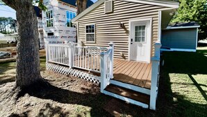 Uma casa pequena, térrea, com deck de madeira e cerca branca de piquete.