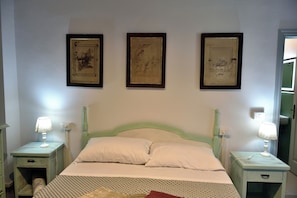A bedroom with a bed, two bedside tables, and three framed pictures on the wall. - White Iron Room · Casa del Fattore, Villa Luzi (Treia)